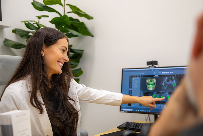 Dr. Mencini smiling and pointing to xrays on the computer